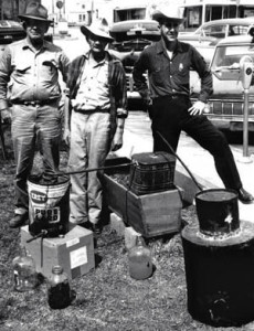 Maryanne (she’s a Justice of the Peace) likes the photo of Grandpa Pinkston with his moonshine still in 1965. Dick Pinkston is surrounded by Robert Taylor, a federal officer, and Sheriff Emmett Edmonds. Pinkston was jailed for 60 days.